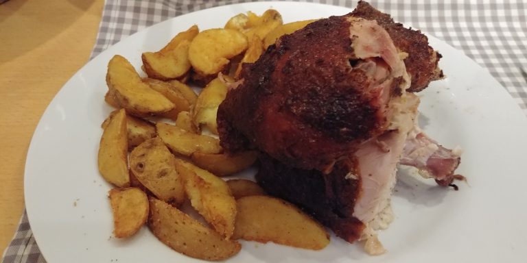 Gebratenes Fleischstück mit knuspriger Kruste und knusprigen Kartoffelspalten.